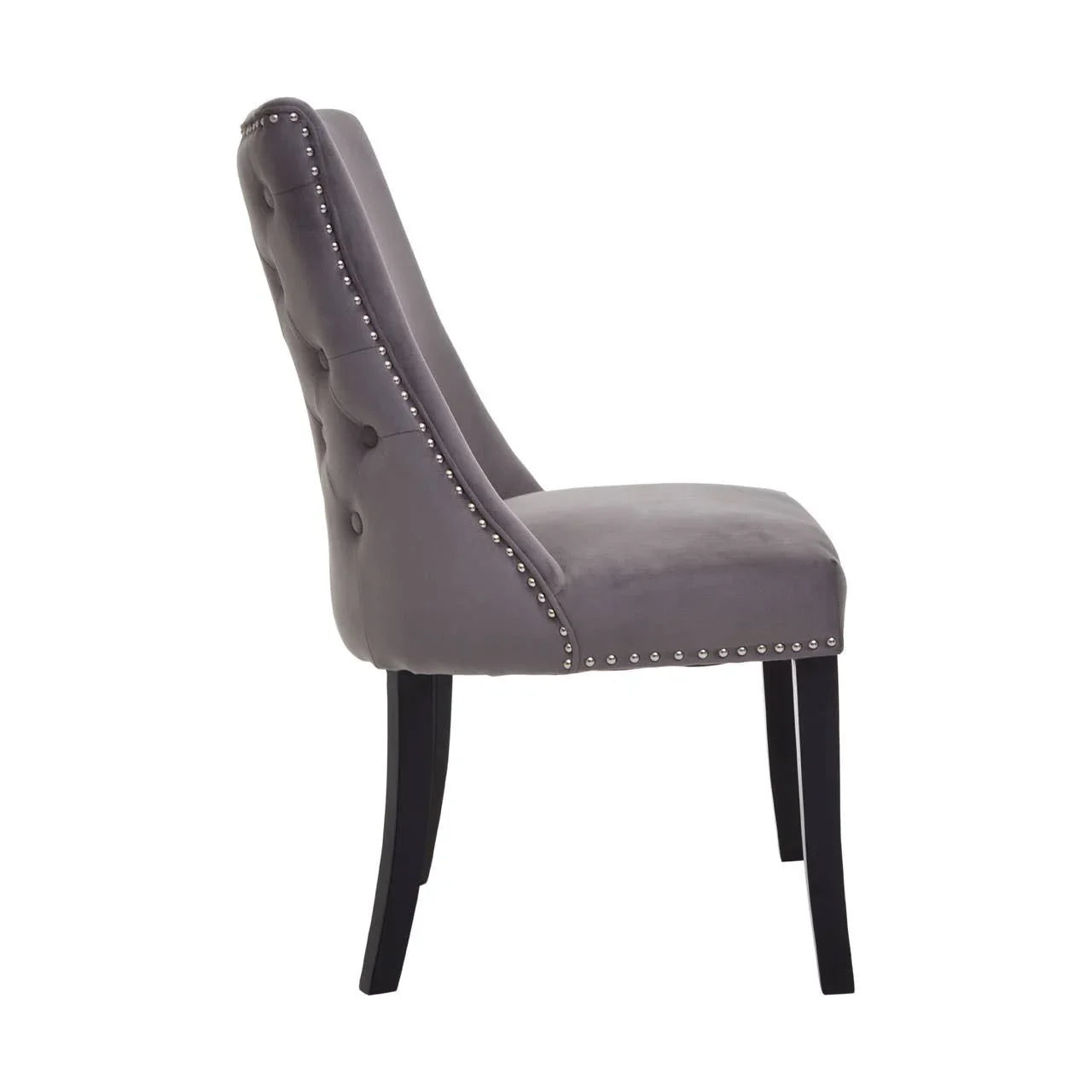 Grey velvet dining chair with button tufted back, silver stud detailing, and black legs side view