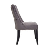 Grey velvet dining chair with button tufted back, silver stud detailing, and black legs side view