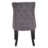 Grey upholstered dining chair with button tufted back and silver stud accents, rear view