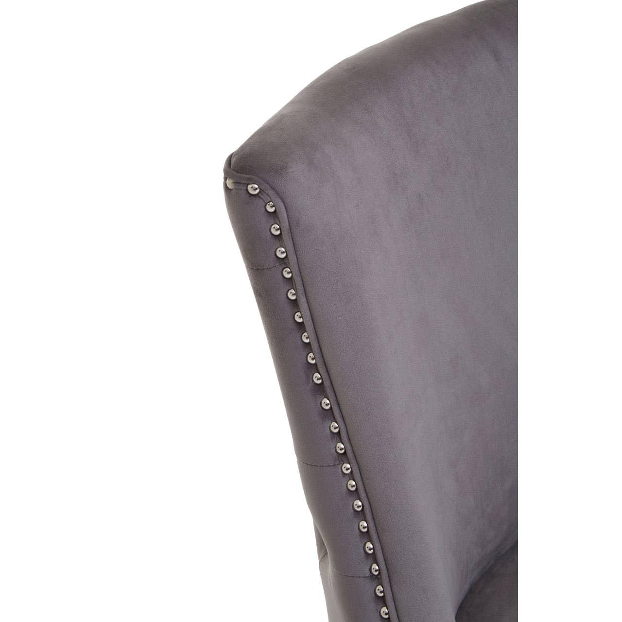 Grey velvet dining chair backrest with silver nailhead trim, close-up detail view