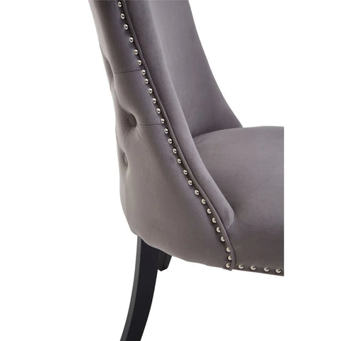 Grey velvet dining chair with button back, silver stud trim and black wooden legs, side view