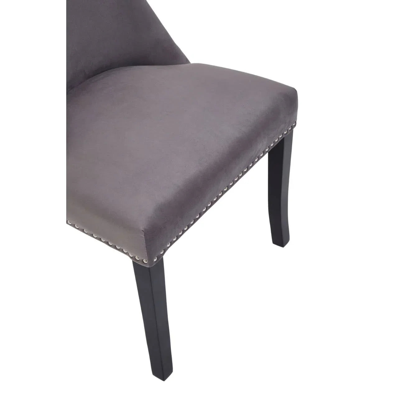 Grey velvet dining chair with studded trim and black wooden legs, close-up view