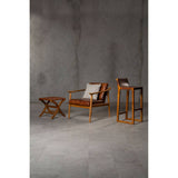 Brown leather bar chair with a teak wood frame, positioned next to a small wooden side table. The chair features a sleek design with a comfortable seat and backrest, while the side table has a minimalist structure. The background is a textured gray wall, enhancing the modern aesthetic of the furniture