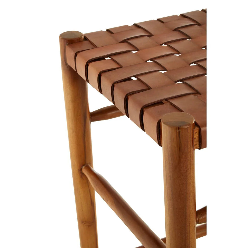Closeup of wooden stool with brown woven leather seat, showing corner and leg detail