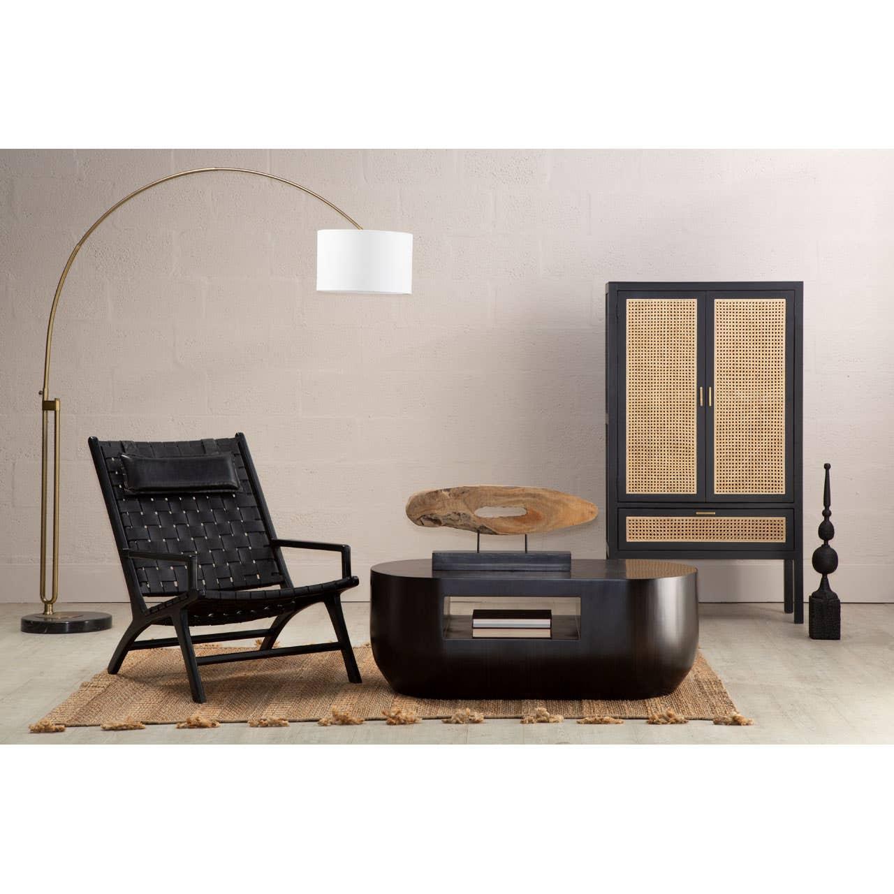 Black lounge chair with woven seat, wooden coffee table, and cane cabinet in modern living room