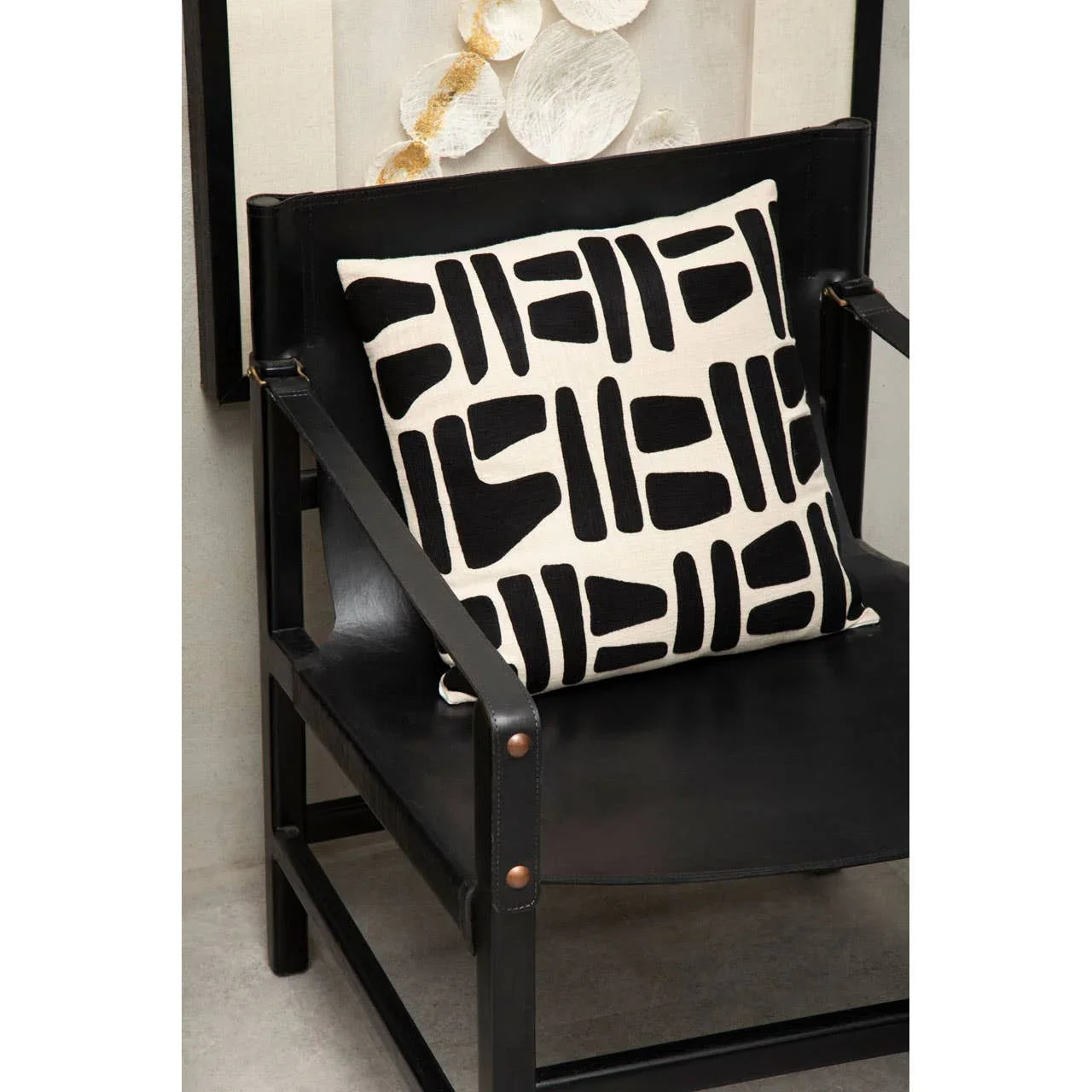 Black leather accent chair with geometric patterned cushion in monochrome decor setting