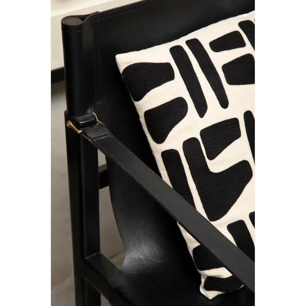 Black leather accent chair with modern black and white patterned cushion