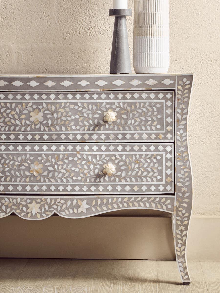 Bone inlay chest of drawers with floral pattern and curved legs against cream wall