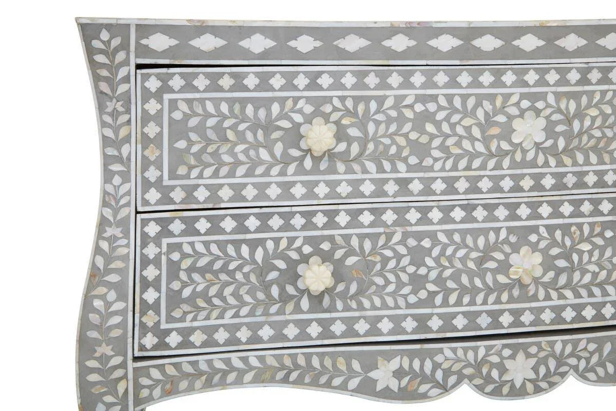 Grey chest of drawers with intricate floral bone inlay design and curved edges