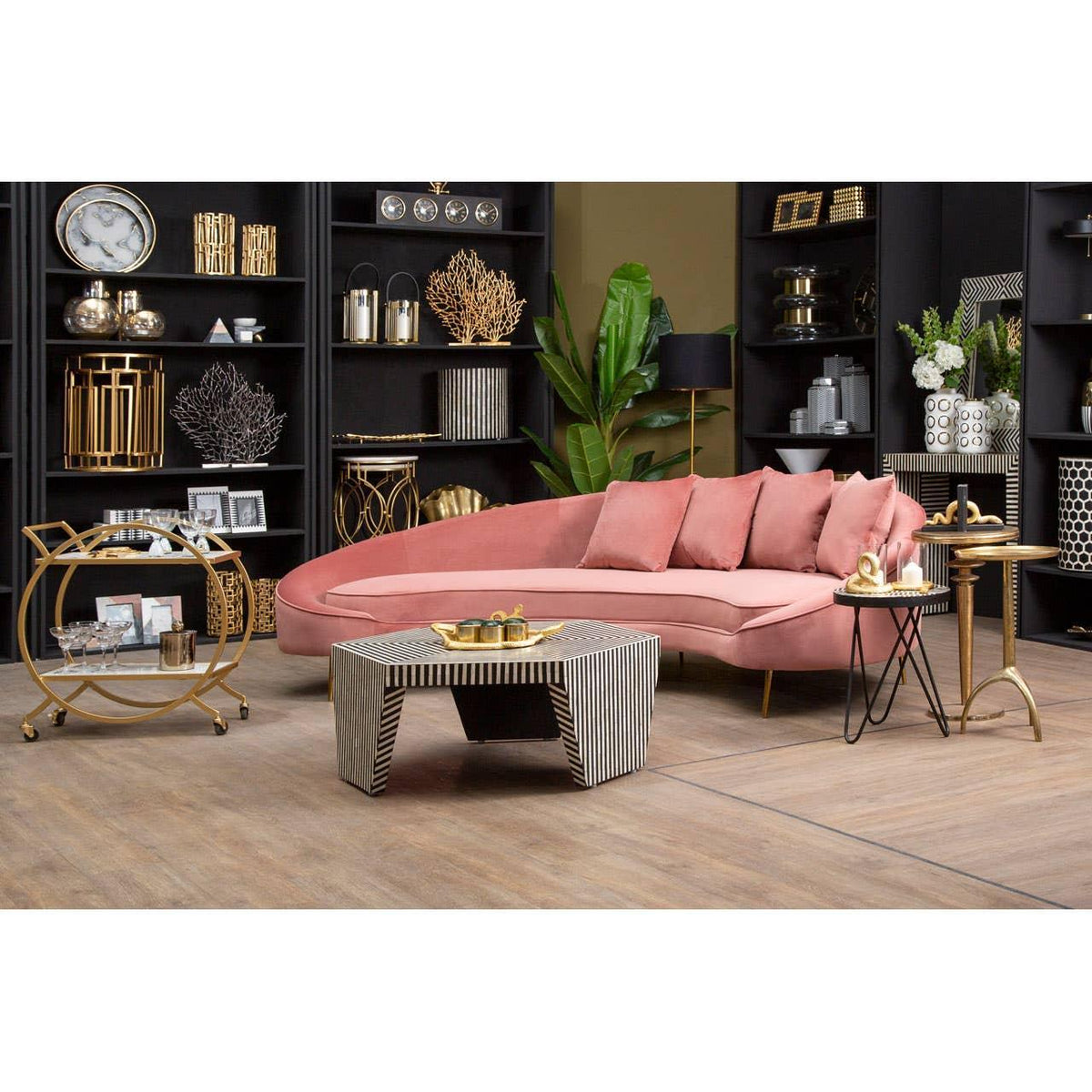 Pink velvet corner sofa with gold coffee table in modern living room with black shelving