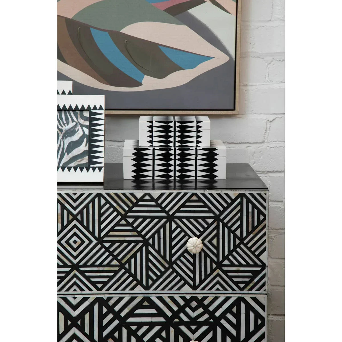 Black and white geometric chest of drawers with decorative boxes and abstract artwork