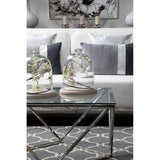 A stylish two-seater sofa in ivory and mink upholstery, positioned in a modern living room setting. The sofa features plush cushions and is complemented by a glass coffee table with decorative items, including two glass cloches and a patterned area rug beneath. The background showcases a piece of wall art and soft lighting, creating an inviting atmosphere