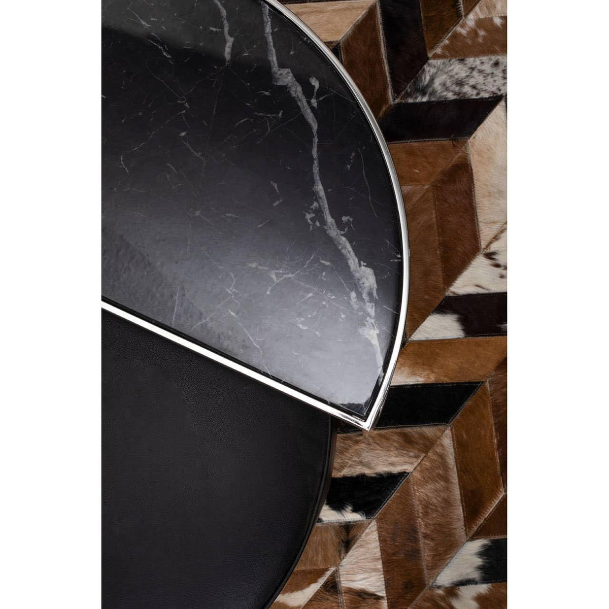 Black marble coffee table with metal trim on geometric cowhide rug