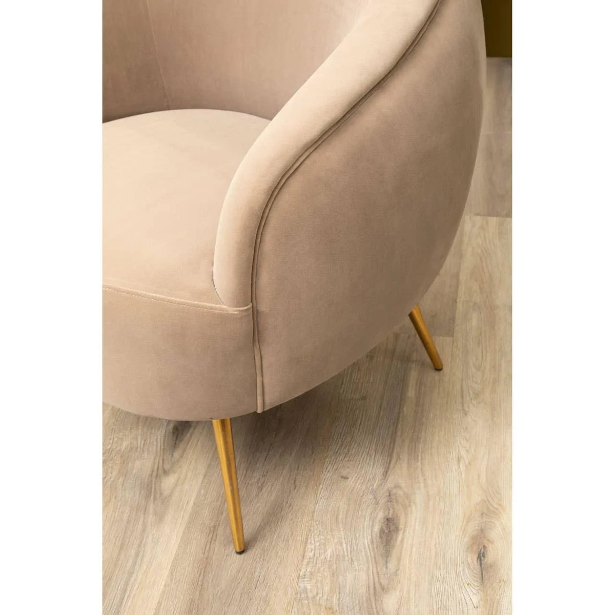 Beige velvet accent chair with gold metal legs on light wood flooring