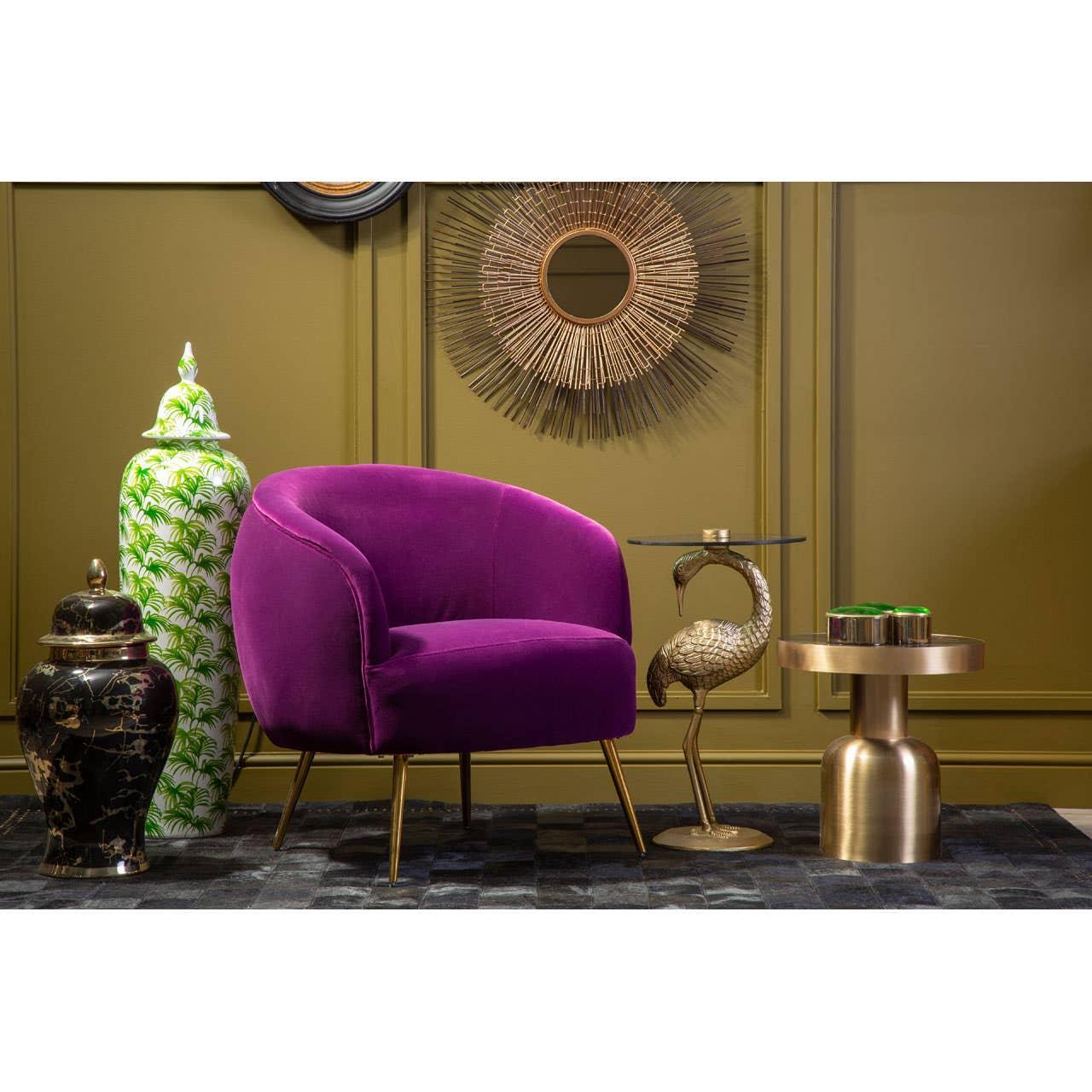 Purple velvet accent armchair with gold legs beside a decorative crane side table