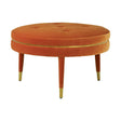 Round footstool upholstered in vibrant orange velvet with a tufted top, featuring tapered wooden legs and gold accents at the base