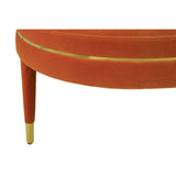 Orange velvet footstool with a curved top and gold trim, featuring tapered wooden legs with gold accents
