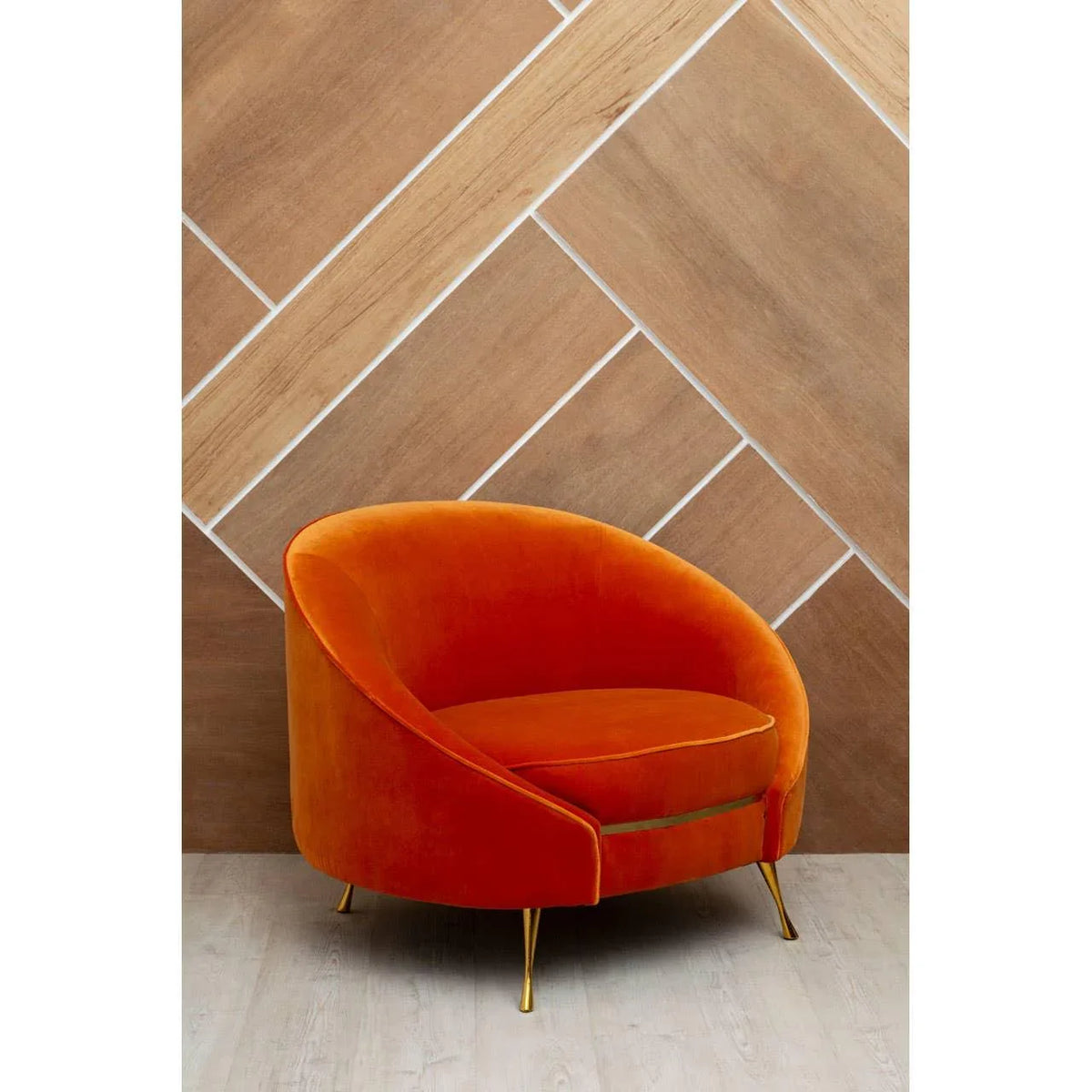 Orange velvet accent chair with gold legs on light wood floor
