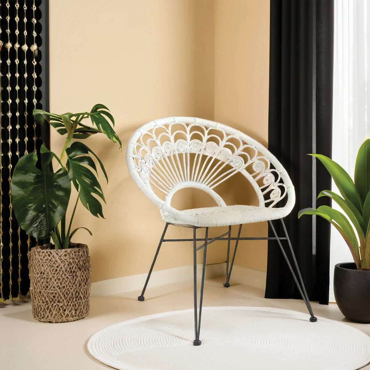 A white natural rattan chair with a curved backrest and metal legs is positioned in a cozy corner, surrounded by a potted plant and a circular rug, against a backdrop of beige walls and black curtains