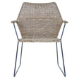 Natural rattan chair with an angled design, featuring a woven seat and backrest, supported by sleek metal legs. The chair has armrests and a light, neutral color that complements various decor styles