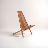 A wooden lounge chair with a tall, slatted backrest and a minimalist design, featuring a natural wood finish and angled legs for stability, set against a plain light background