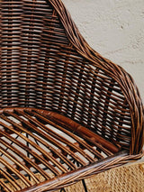 A close-up view of the Manado Natural Croco Rattan Chair, showcasing its intricate woven design and natural brown tones. The chair features a curved backrest and a sturdy seat made from rattan, highlighting the craftsmanship and texture of the material against a neutral background