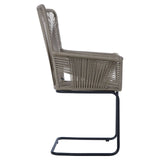 Side view of the Manado Rattan Effect Chair featuring a woven rattan design in a neutral color, supported by a sleek black metal frame. The chair has a high backrest and armrests, showcasing a modern and stylish aesthetic suitable for home decor