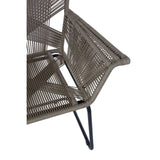 A close-up view of the Manado Rattan Effect Chair, showcasing its textured rattan-style seat and backrest, with a sleek black metal frame and armrest. The design features a modern, minimalist aesthetic suitable for indoor or outdoor use