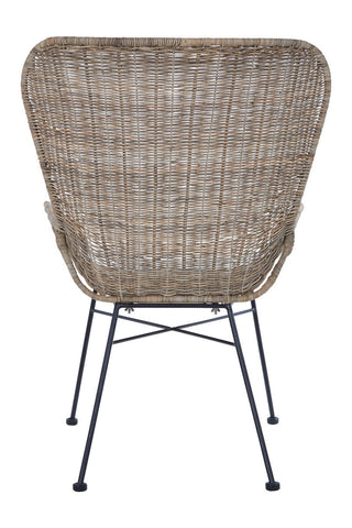 Curved back of a natural rattan chair showcasing a woven texture, supported by slender metal legs. The chair's design emphasizes a modern aesthetic with a natural finish