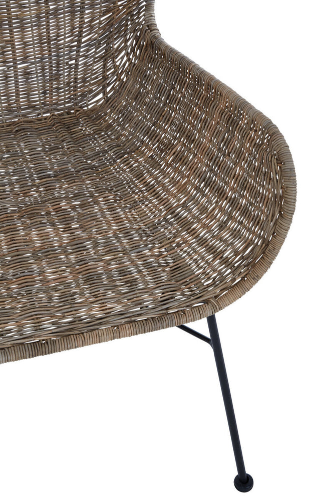 Curved seat of a natural rattan chair with a textured surface, supported by slender black metal legs. The design showcases a warm, earthy tone and a modern aesthetic suitable for home decor