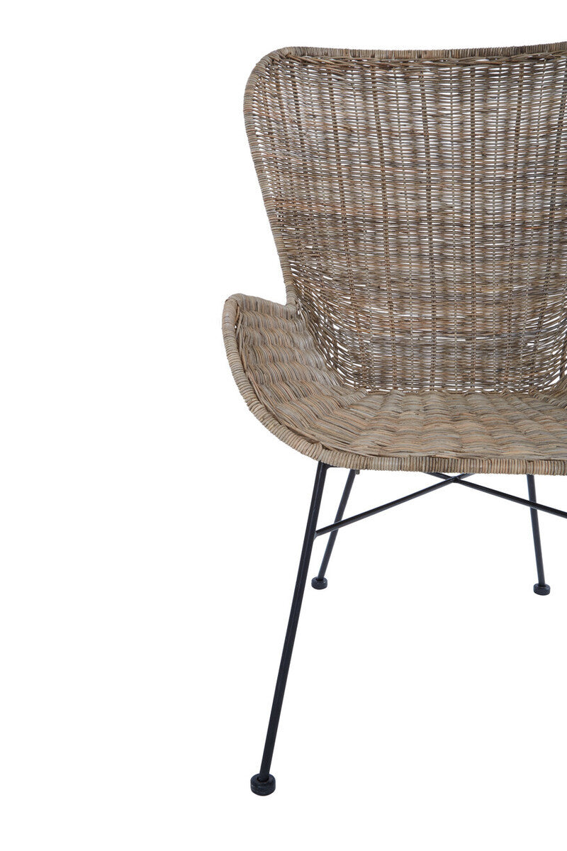Curved backrest of a natural rattan chair with a textured weave, supported by slender black metal legs. The chair features a minimalist design, showcasing the organic material and elegant shape