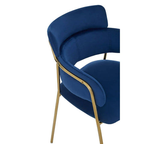 Blue velvet dining chair with gold metal legs and curved backrest, side angle view