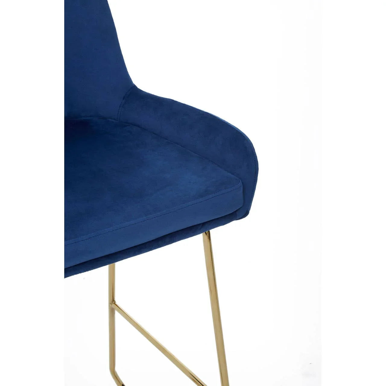 Blue velvet dining chair with gold metal legs, close-up of seat and armrest