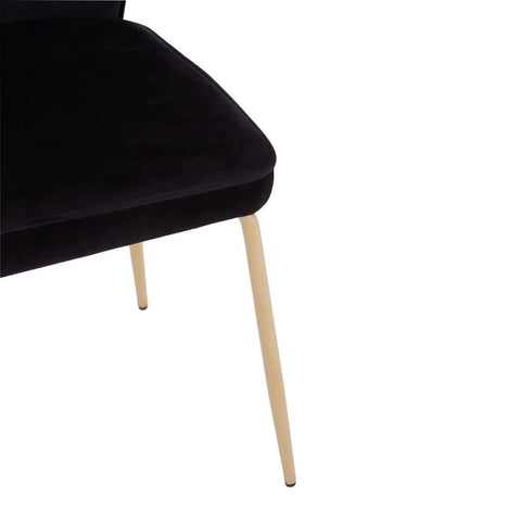 Black velvet dining chair with slim gold metal legs, partial close-up view