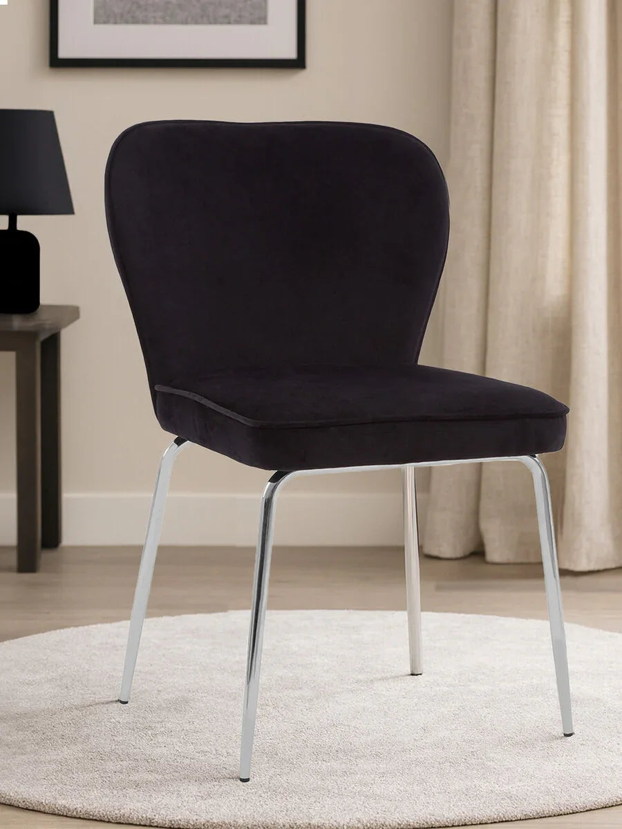 Black velvet dining chair with chrome legs on light rug in modern room setting