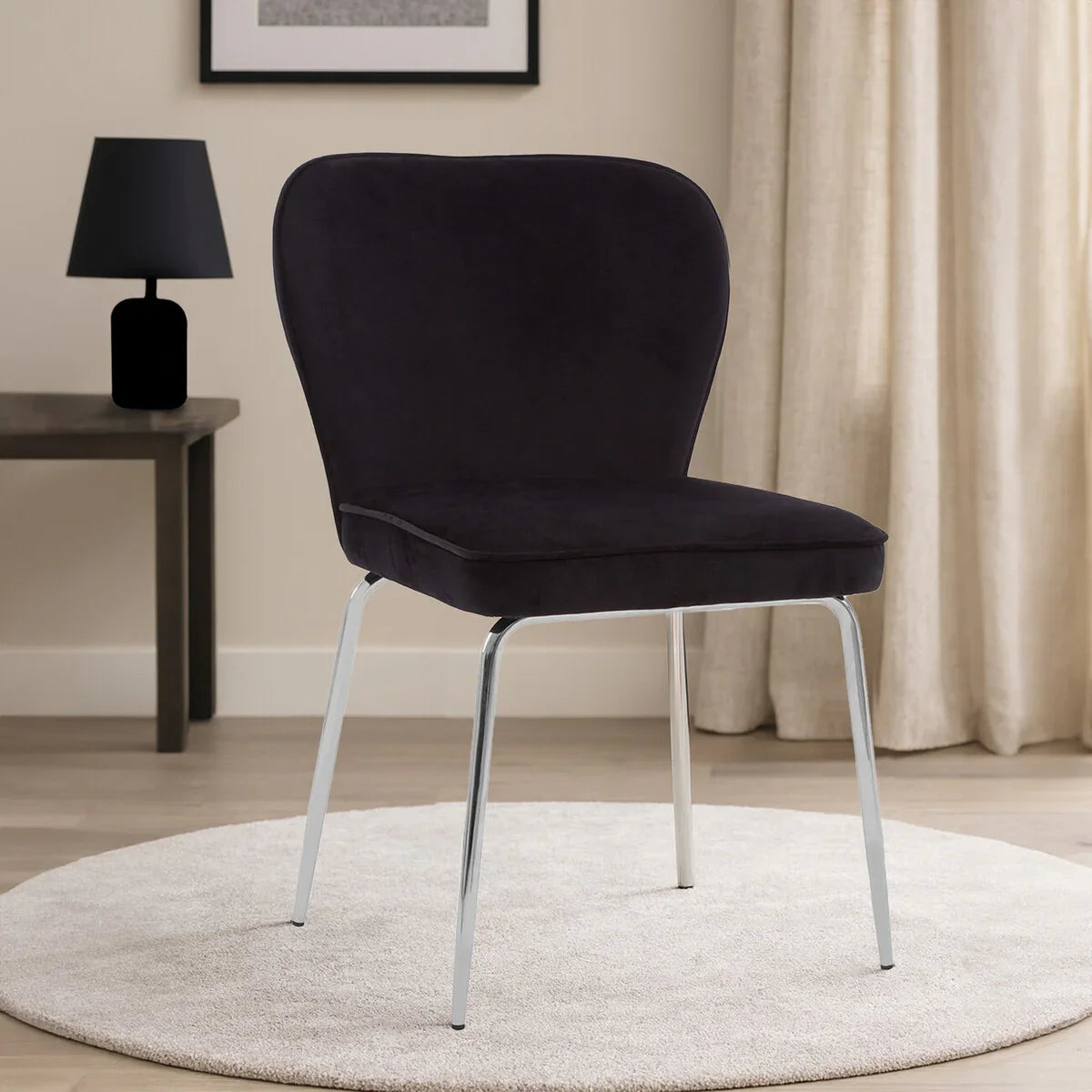 Black velvet dining chair with chrome legs on round rug in modern living room setting