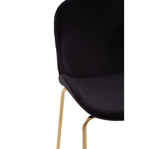 Black velvet dining chair with curved back and gold metal legs, close-up view