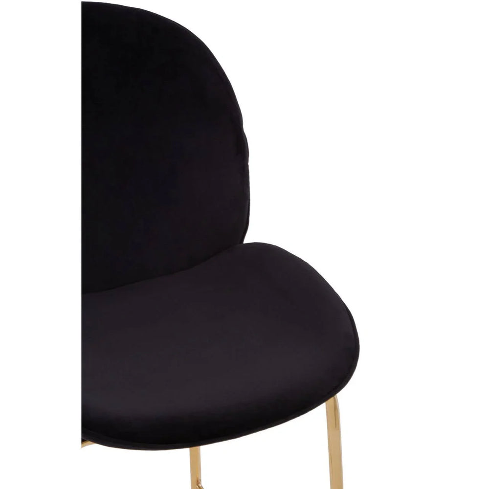 Close-up of black velvet dining chair with gold metal legs