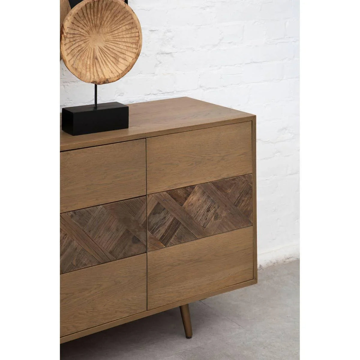 Brown wooden sideboard with chevron pattern drawers and decorative wooden sculpture