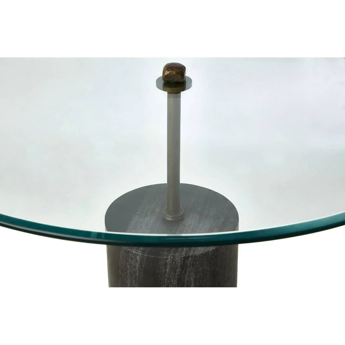 Closeup of glass dining table with metal support and marble-effect cylindrical base