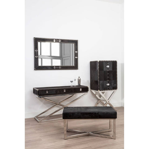 A stylish drinks cabinet featuring a hair-on leather exterior with a cross base design, complemented by a sleek mirror and a matching console table. The cabinet has two doors and is set against a light-colored wall, with a wooden floor visible beneath