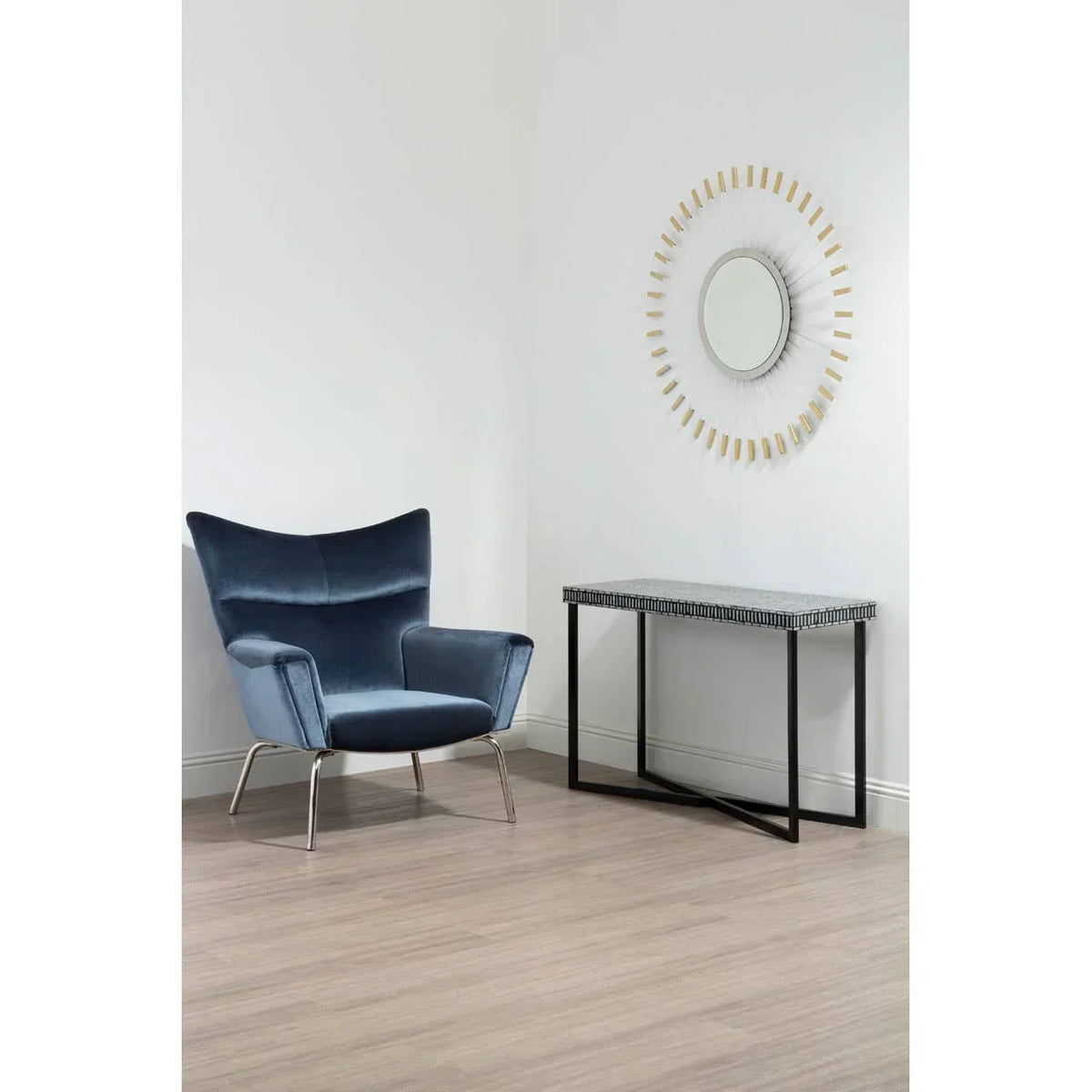 Blue velvet accent chair beside modern console table and round wall mirror in bright room