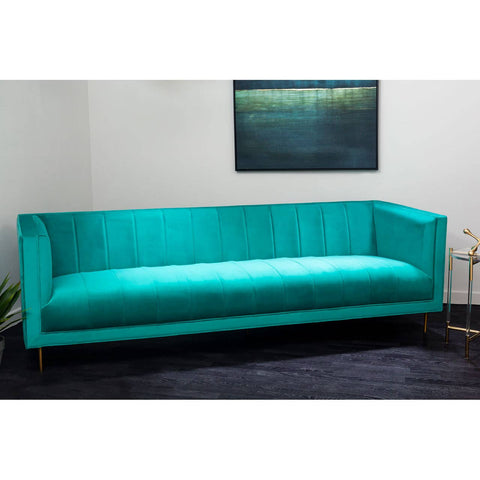 A vibrant green three-seat sofa with a sleek, modern design, featuring a smooth fabric upholstery and minimalist wooden legs. The sofa is positioned against a light-colored wall, with a piece of abstract art hanging above it, and a dark rug underneath