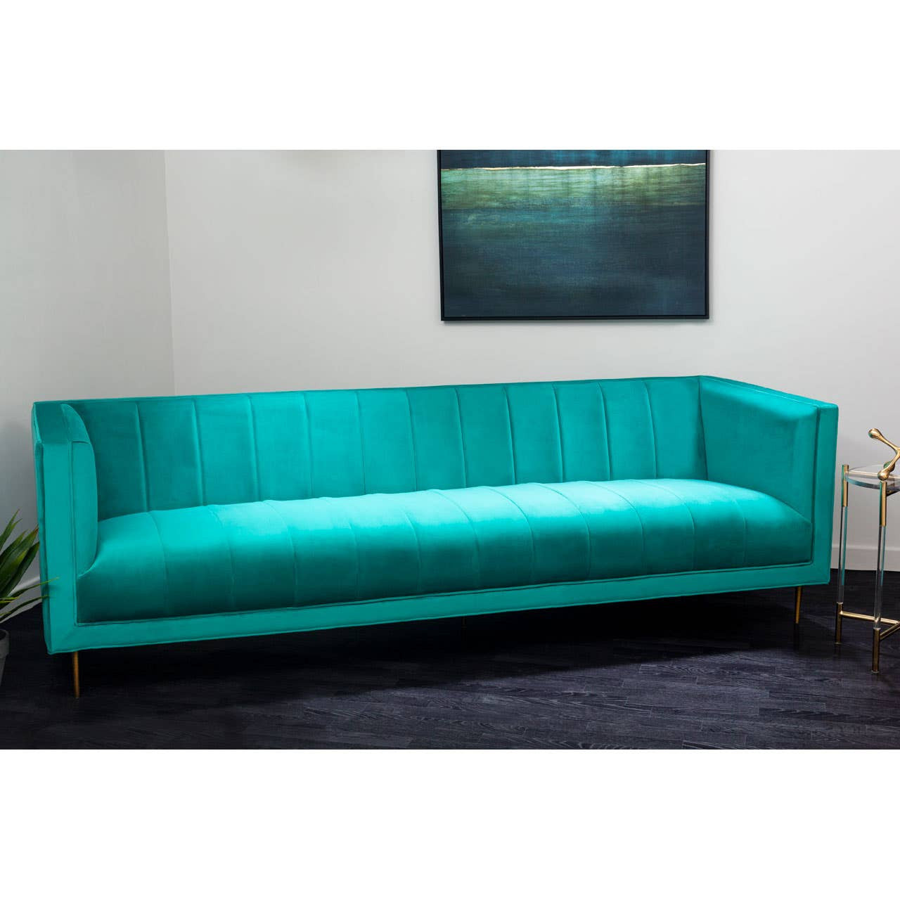 A vibrant green three-seat sofa with a sleek, modern design, featuring a smooth fabric upholstery and minimalist wooden legs. The sofa is positioned against a light-colored wall, with a piece of abstract art hanging above it, and a dark rug underneath