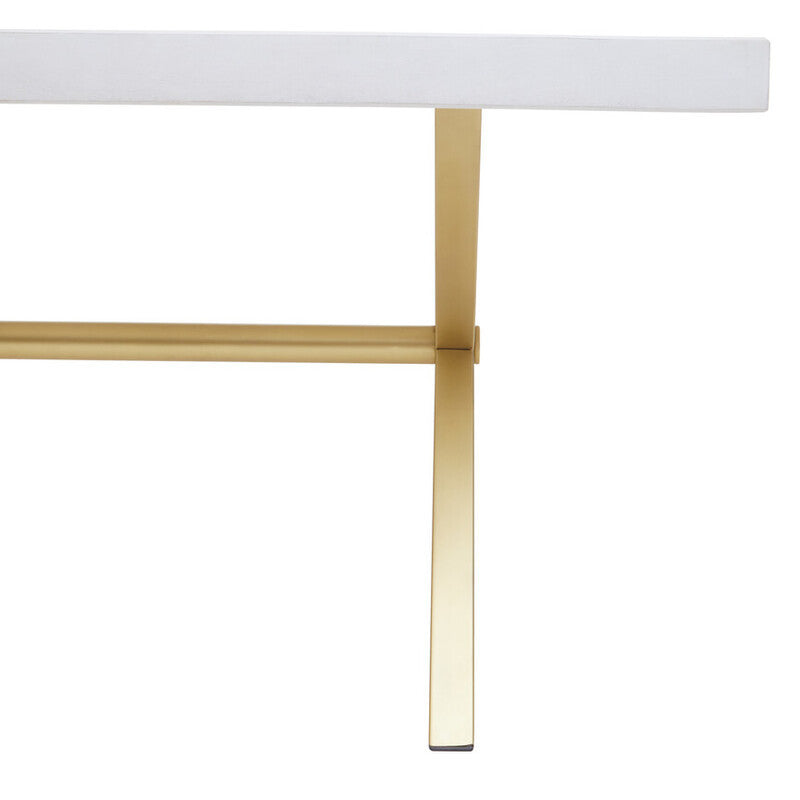 A close-up view of a dining table featuring a white-washed mango wood top with a smooth finish, supported by sleek, gold-toned metal legs that provide a modern contrast. The design highlights the natural grain of the wood and the elegant lines of the table's structure