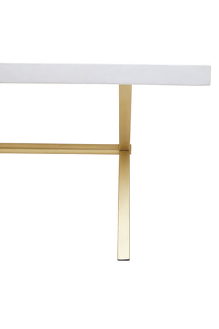 A close-up view of a dining table featuring a white-washed mango wood top with a smooth finish, supported by sleek, gold-toned metal legs that provide a modern contrast. The design highlights the natural grain of the wood and the elegant lines of the table's structure