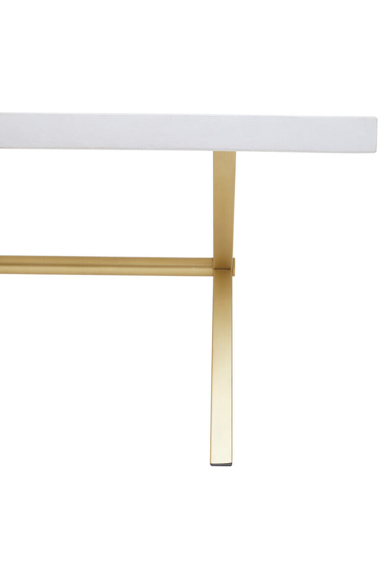 A close-up view of a dining table featuring a white-washed mango wood top with a smooth finish, supported by sleek, gold-toned metal legs that provide a modern contrast. The design highlights the natural grain of the wood and the elegant lines of the table's structure