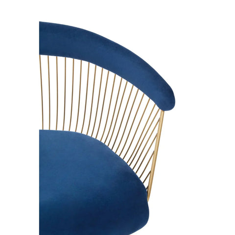 Velvet accent chair with blue cushion and gold metal spindle backrest, close-up view