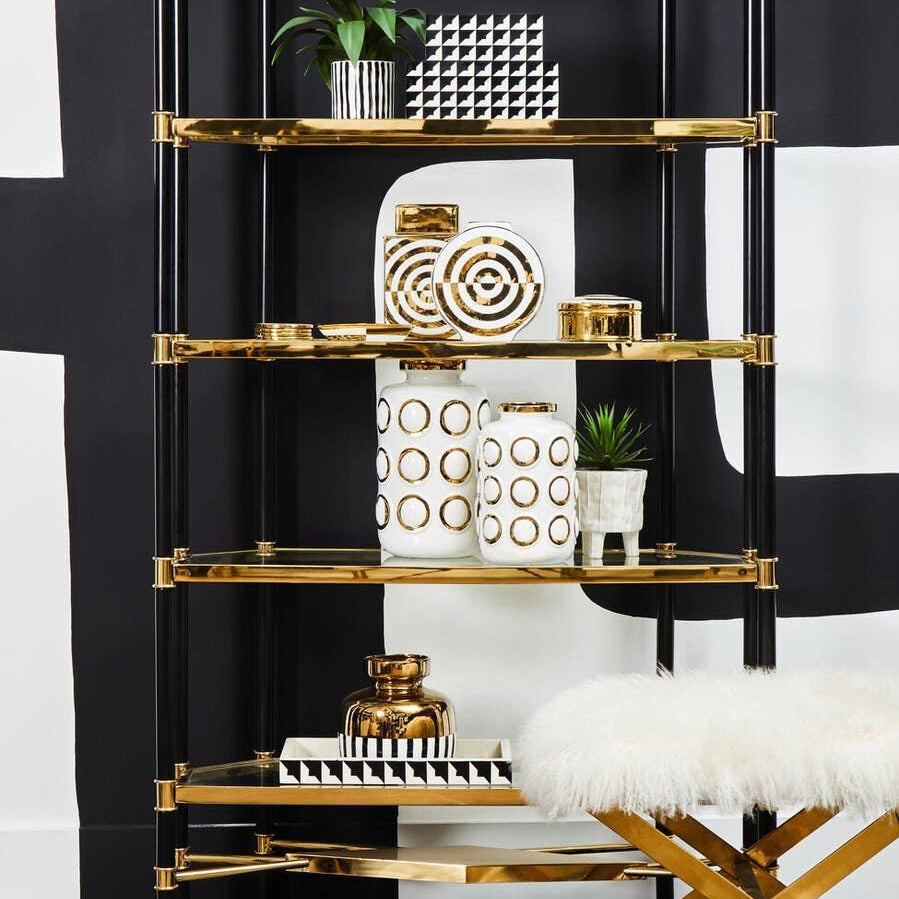 Black and gold shelving unit with decorative vases, plant, and geometric tray in modern room