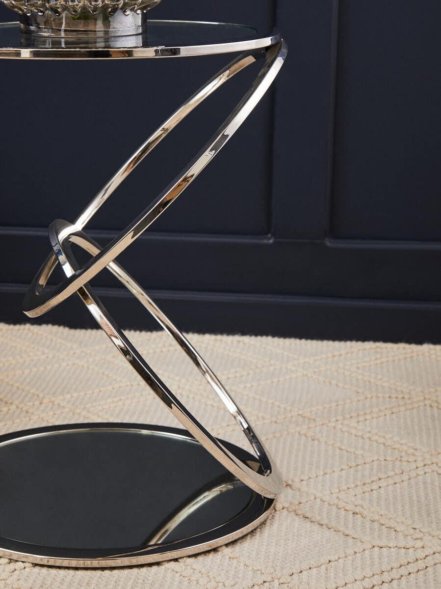 Modern glass side table with chrome spiral base on textured cream rug